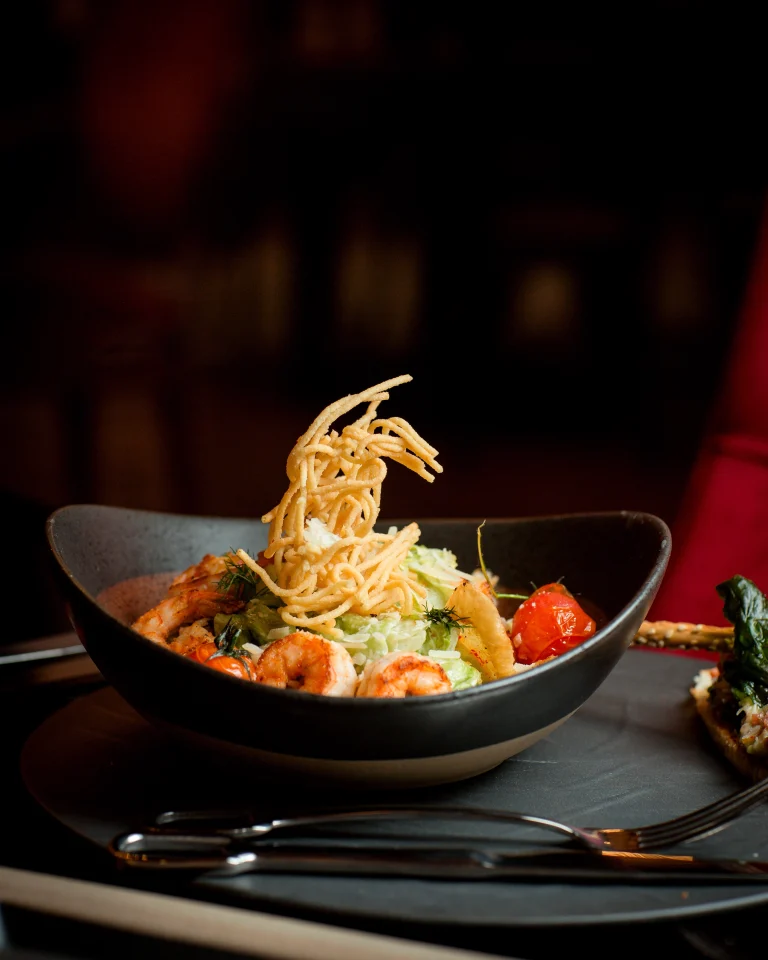 side-view-shrimp-caesar-plate-topped-with-potato-shoestrings